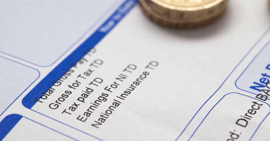 Close-up of a payroll statement highlighting Spain payroll taxes with coins representing salary.