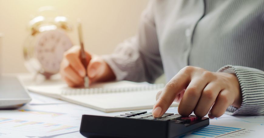 Accountant calculating tax obligations to meet Spain tax year deadlines, with focus on calculator and financial documents