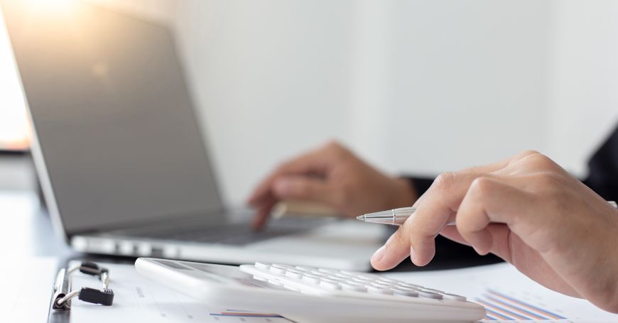 usiness professional calculating IAE tax in Spain using a calculator and laptop with financial charts