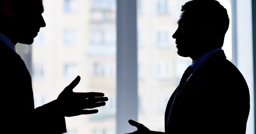 Silhouette of two business people negotiating in an office setting, illustrating alternative dispute resolution in Spain.