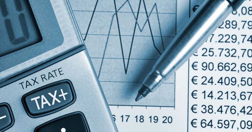 Calcolatrice con pulsante "TAX" e una penna sopra un documento con grafico e numeri in euro, simbolo delle differenze IVA in Spagna.