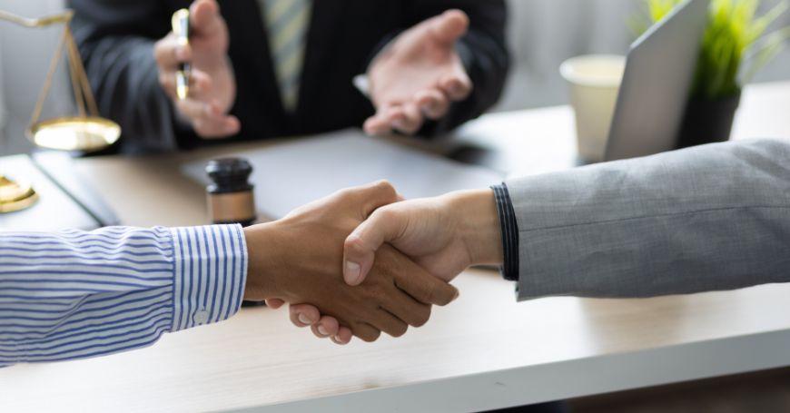 Stretta di mano tra due persone in un ufficio legale, segno di accordo su pignoramento in Spagna.
