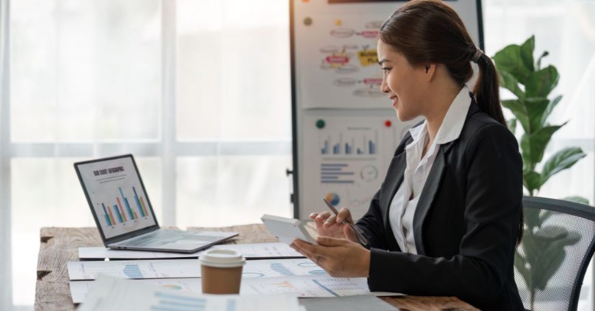 Businesswoman reviewing financial charts on a laptop, discussing form 720 compliance.
