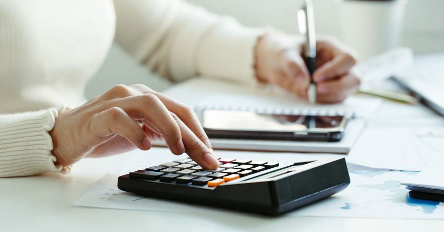 Close-up of hands calculating figures on paper, focusing on modelo 720 submission process.