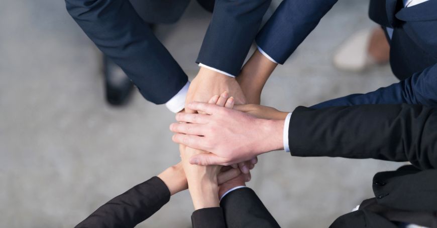 Team di professionisti unisce le mani in segno di collaborazione, rappresentazione visiva di una società di persone in spagna.