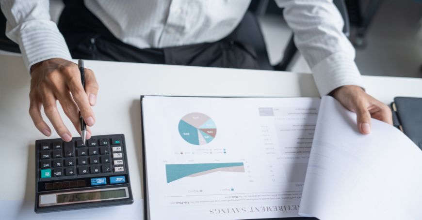 Professionista che calcola le responsabilità fiscali sui dividendi utilizzando una calcolatrice e documenti finanziari per la tassa sui dividendi in Spagna